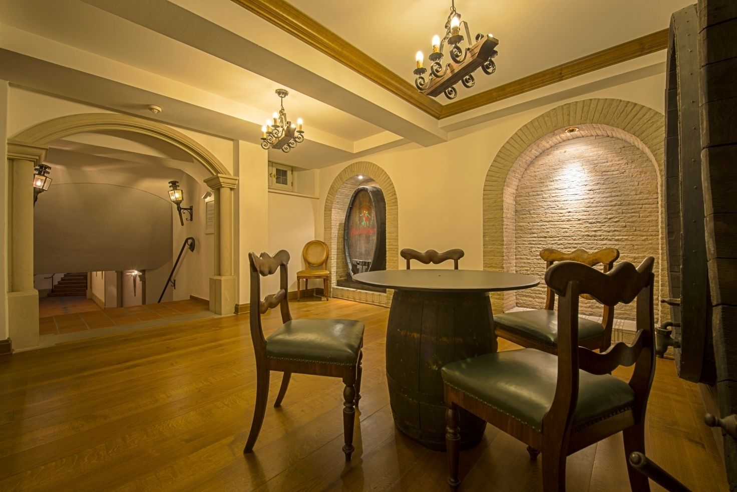A dining area with a round table and four chairs, wooden flooring, and a brick wall.