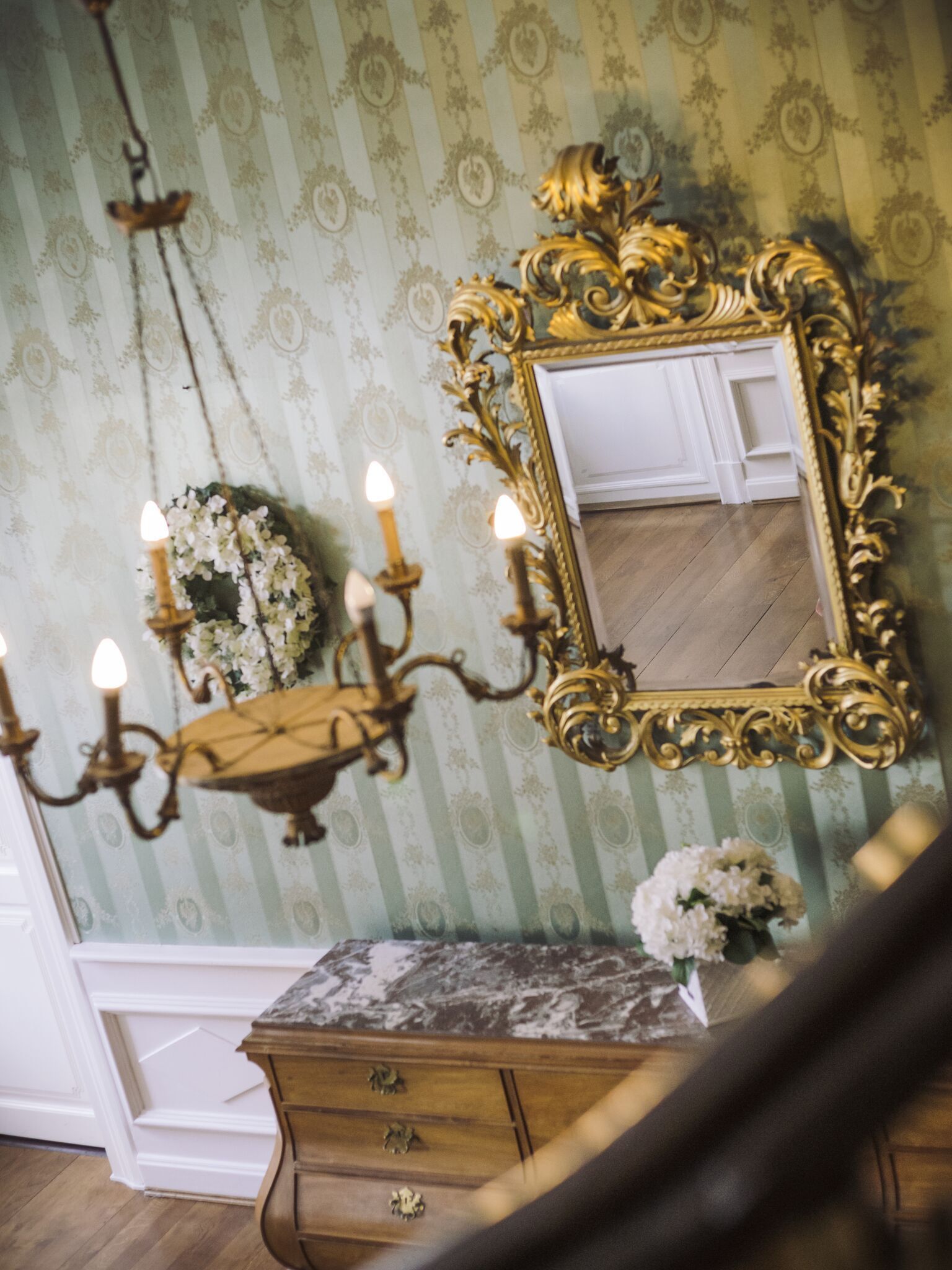 Een kamer met een spiegel, een kroonluchter en een kaptafel.