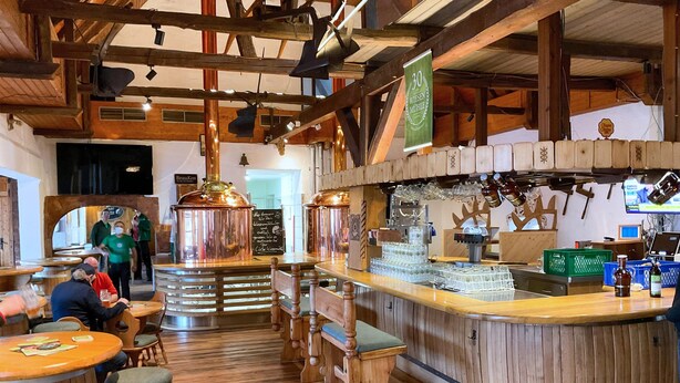 A rustic bar area with wooden furniture, copper beer taps, and a chalkboard menu. - Brauhaus Wiesenmühle (Fulda)