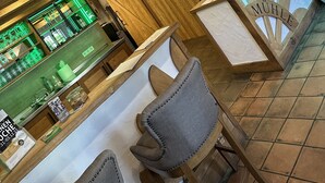 A reception area with wooden beams, a reception desk, and a bar area with green lighting. - Brauhaus Wiesenmühle (Fulda)