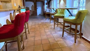 A cozy interior with wooden beams, a tiled floor, and a mix of red and green upholstered chairs. - Brauhaus Wiesenmühle (Fulda)