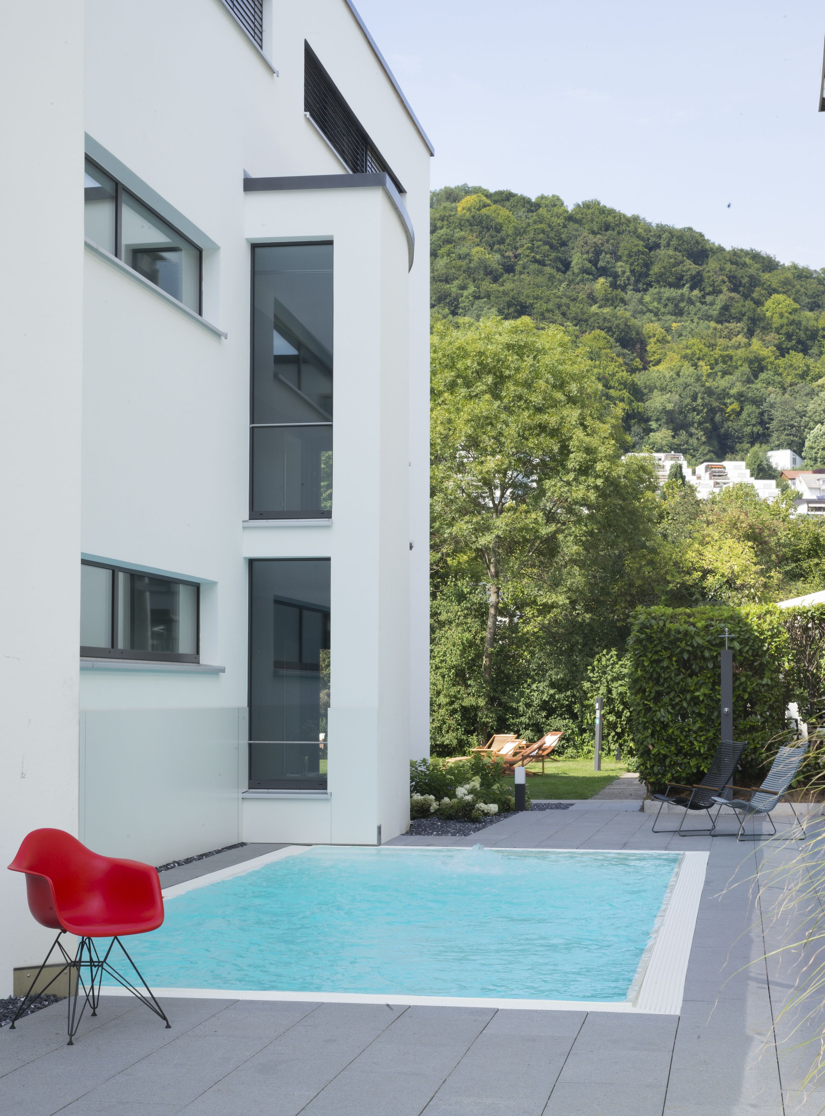 Una piscina al aire libre, sombrillas, sillones reclinables de piscina