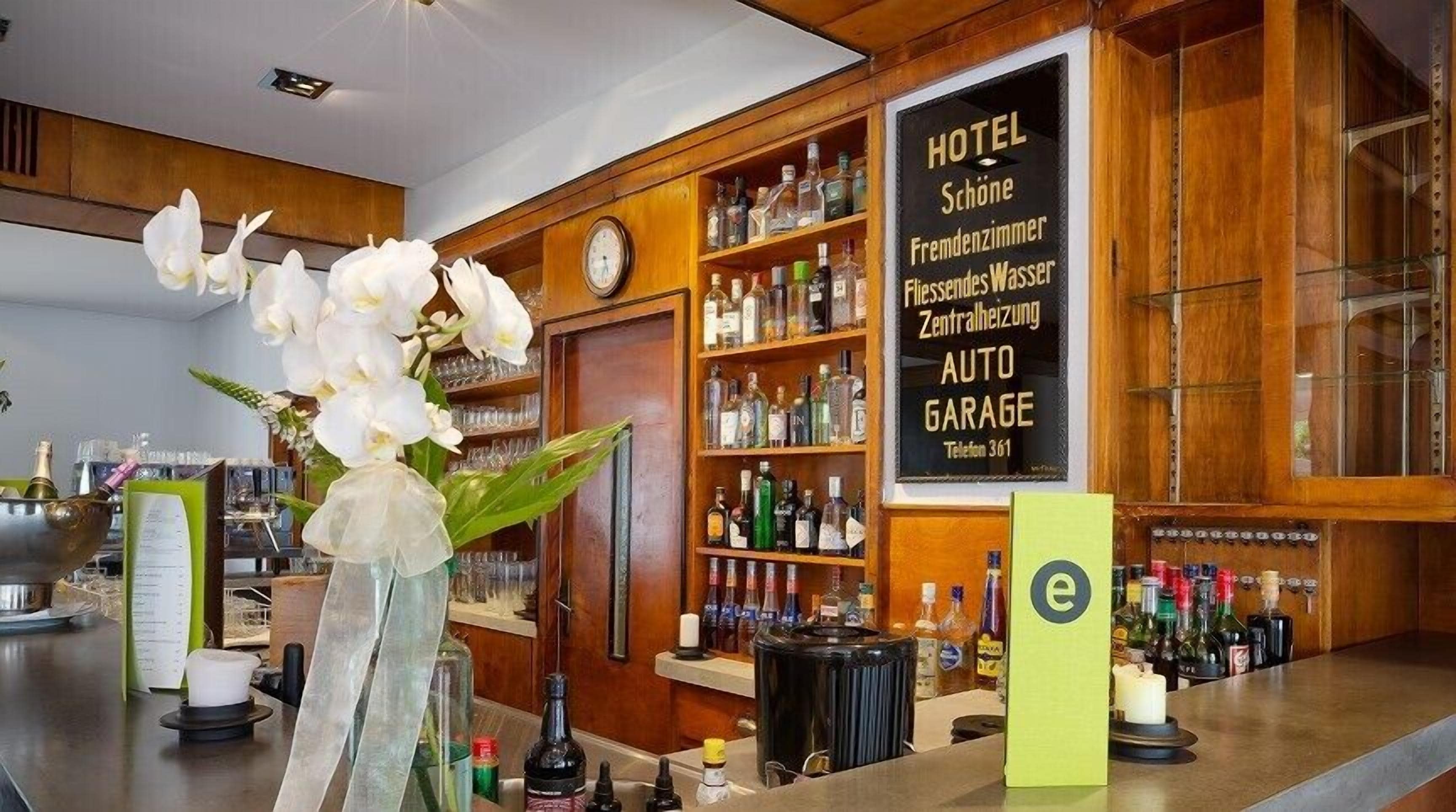 A hotel bar with a wooden interior, a clock, and a sign listing amenities like a minibar, central heating, and an auto garage.