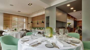 Un restaurante con mesas redondas dispuestas para comer, con manteles blancos y cubiertos.