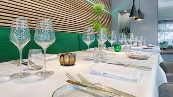 Een eettafel gedekt met verschillende wijnglazen, een gouden schaal en bestek.