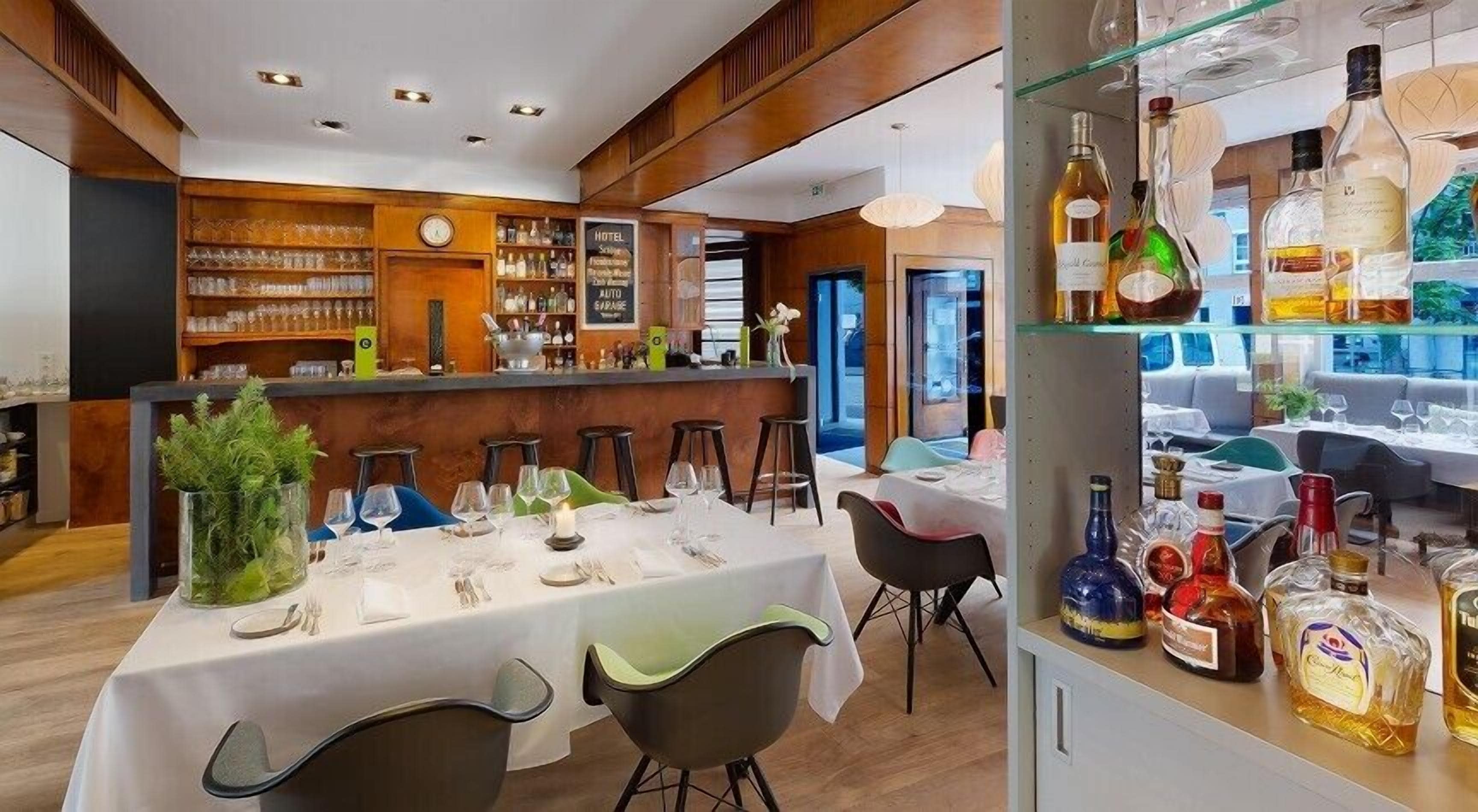 Een restaurant met een bar, gedekte tafels en een divers aanbod aan flessen.