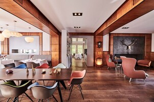 Un comedor moderno con paneles de madera, chimenea y vista a la cocina.