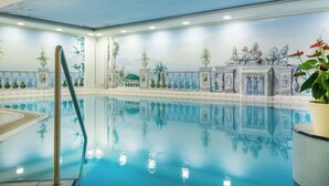 Une piscine intérieure ornée d’une fresque représentant un bâtiment classique et de colonnes.