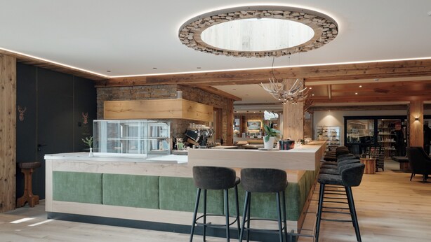 Une cuisine moderne dotée d’un îlot central, de tabourets de bar et d’un luminaire circulaire au design original.