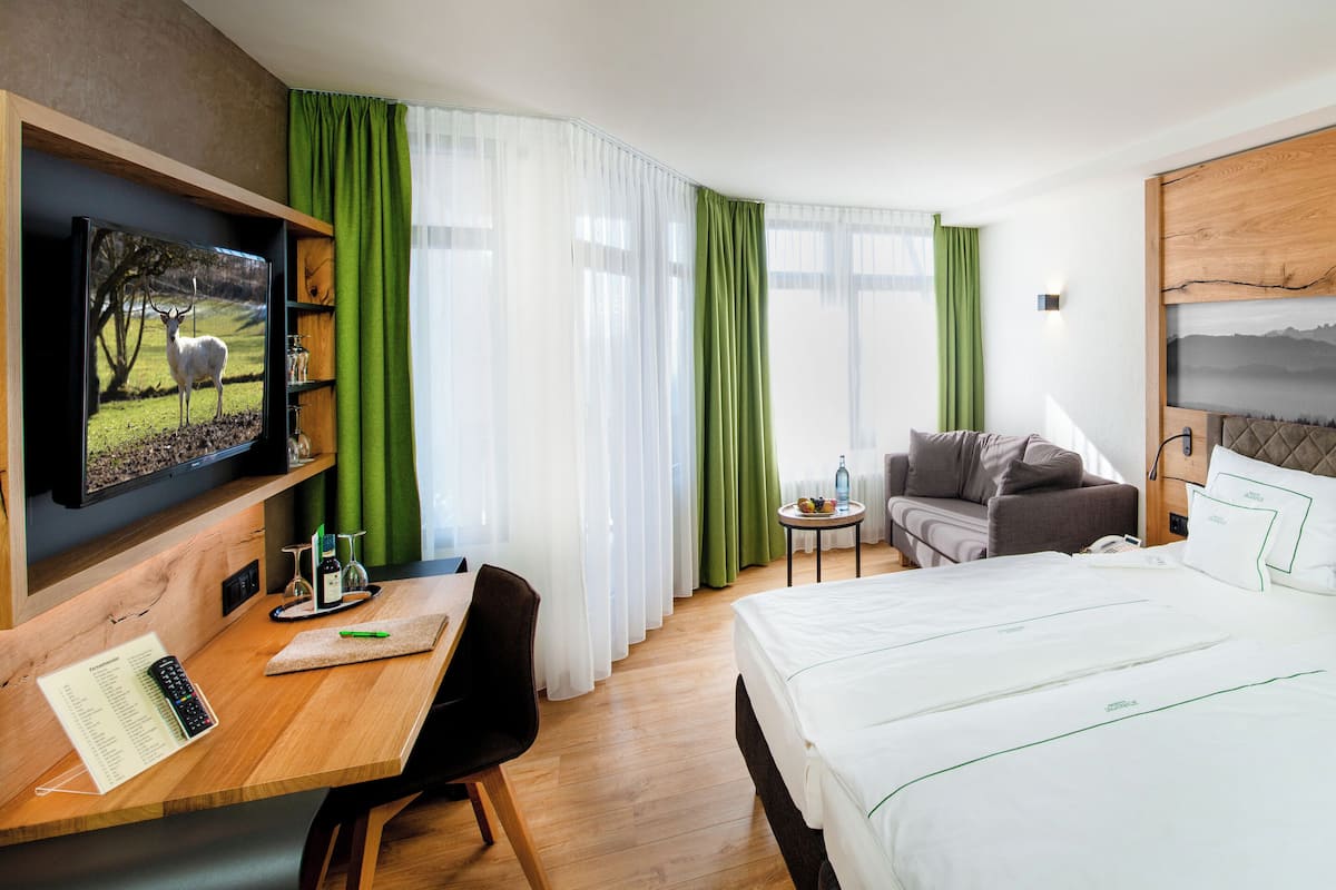 Une chambre d’hôtel avec un lit, un bureau avec un ordinateur, une télévision et un tableau au mur.
