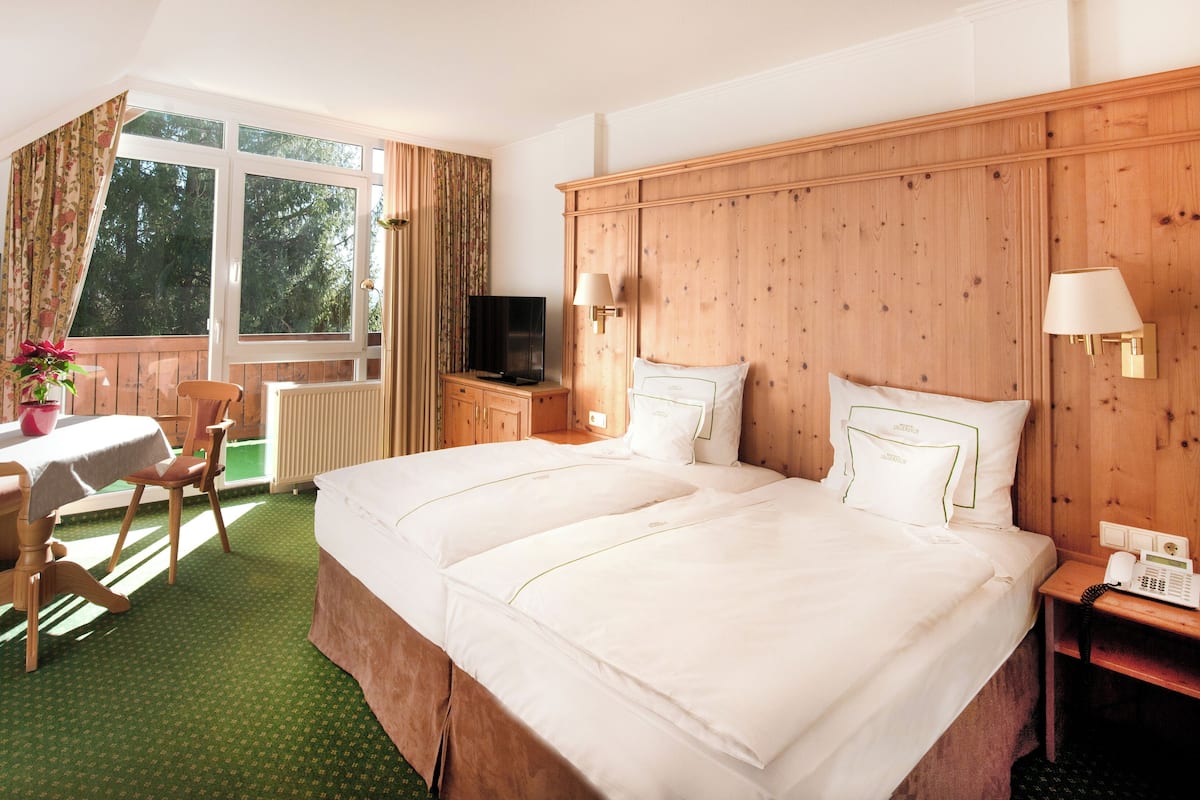 Une chambre d’hôtel avec deux lits, un bureau avec une chaise, une télévision et une fenêtre avec des rideaux.