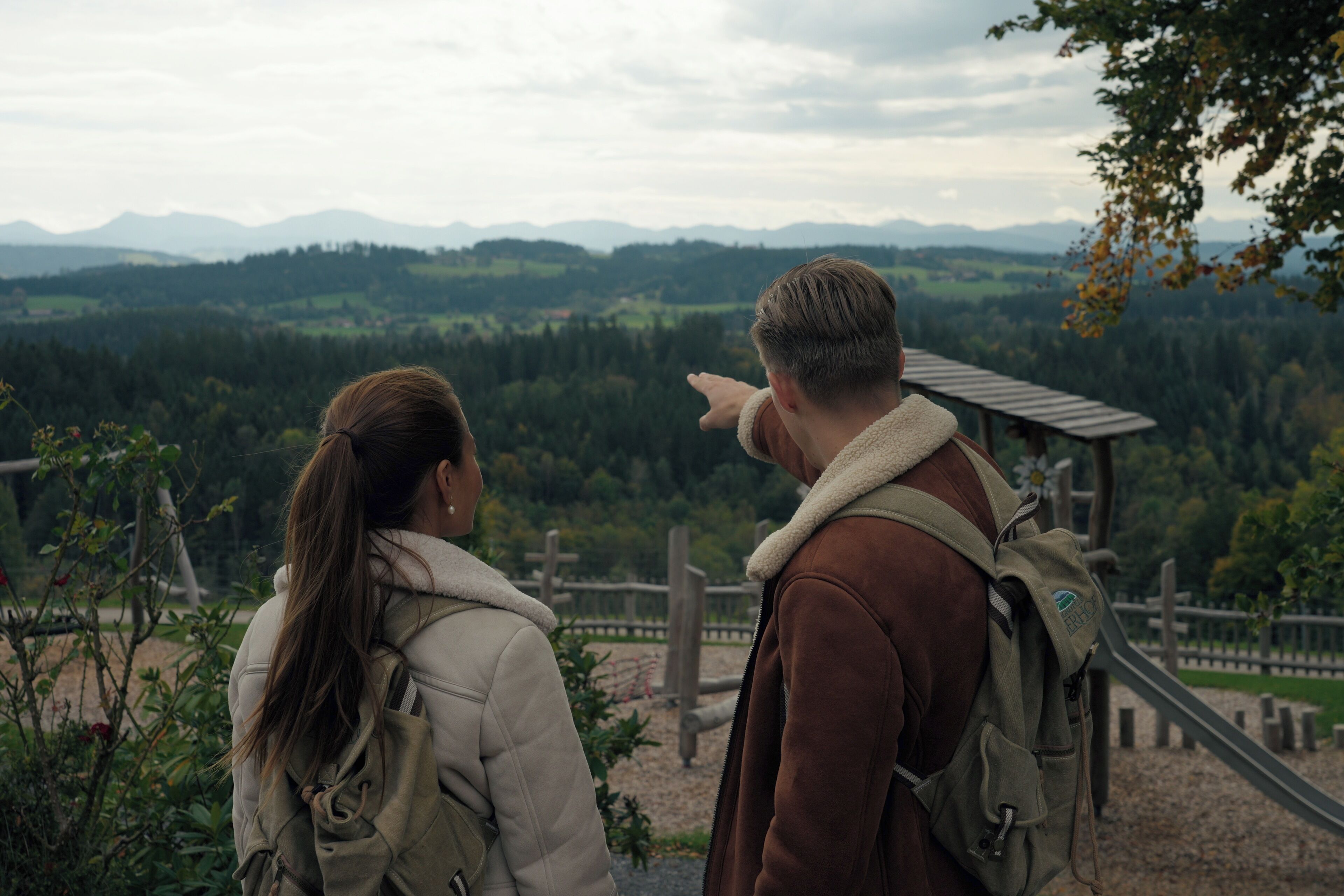 Dos personas de pie en un mirador con vistas a un paisaje montañoso.
