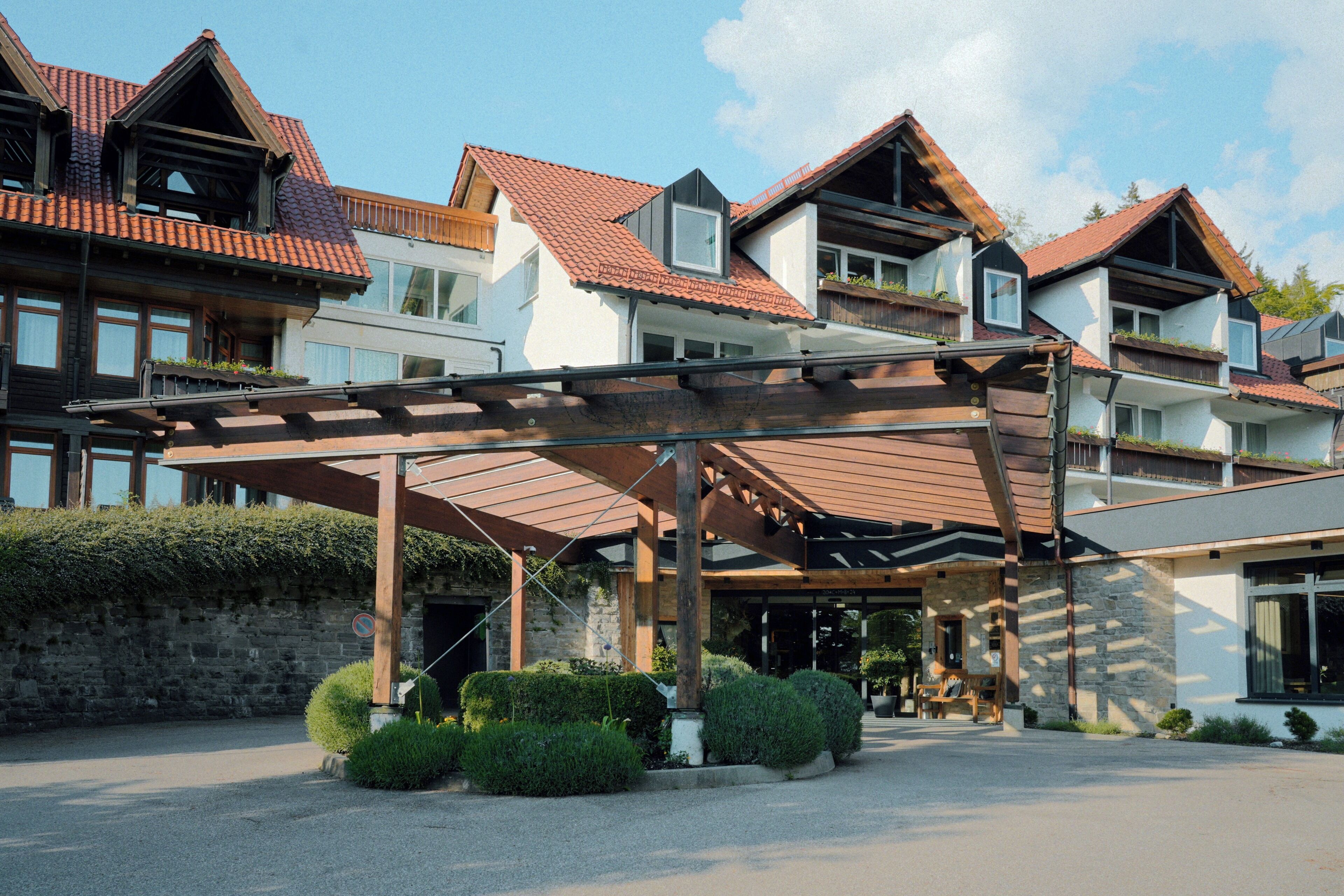 Ein mehrstöckiges Hotel mit überdachter Eingangspartei, Steinmauern und einem roten Ziegeldach.