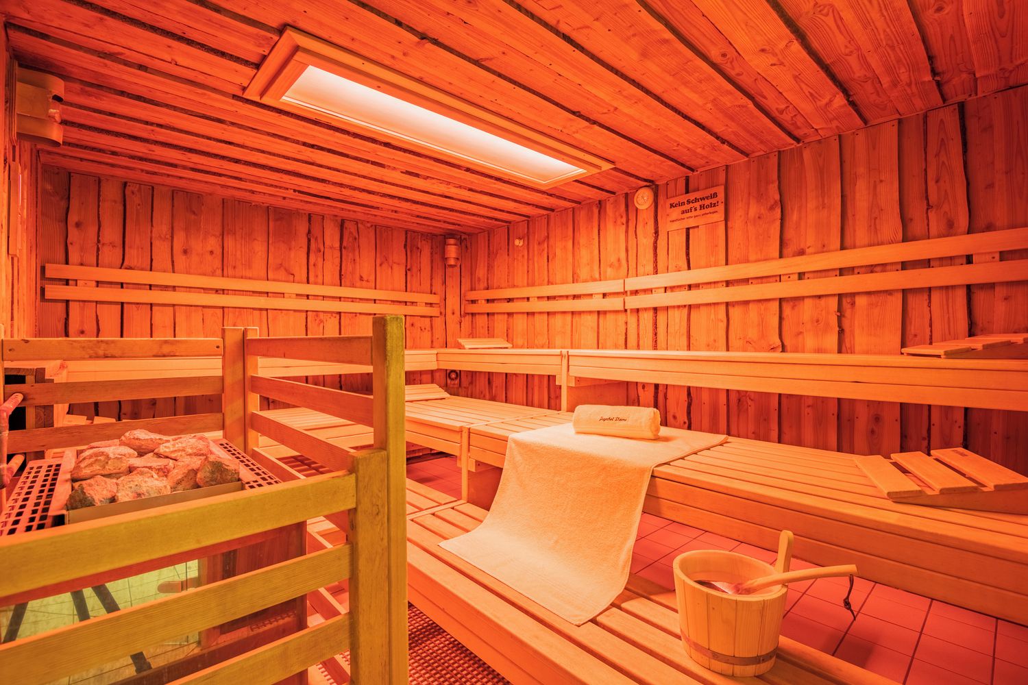 Een sauna met houten banken, een handdoek en een emmer.