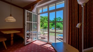 A room with a large sliding glass door leading to an outdoor patio area. - Strandhotel Seehof (Pfofeld)