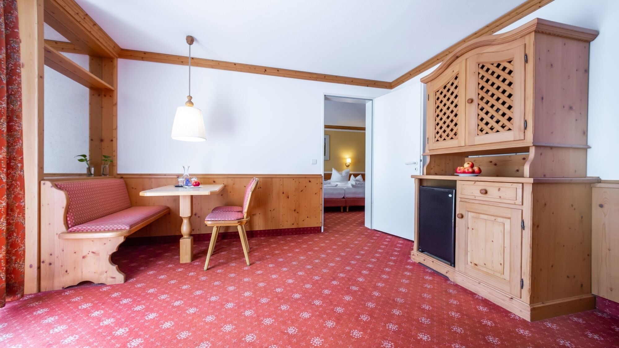 A cozy room with a wooden bench, a small table, and a cabinet with a lattice design.