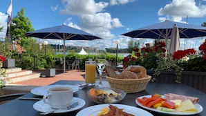Un tavolo da pranzo all'aperto con cibo per la colazione, due ombrelloni e una vista panoramica.