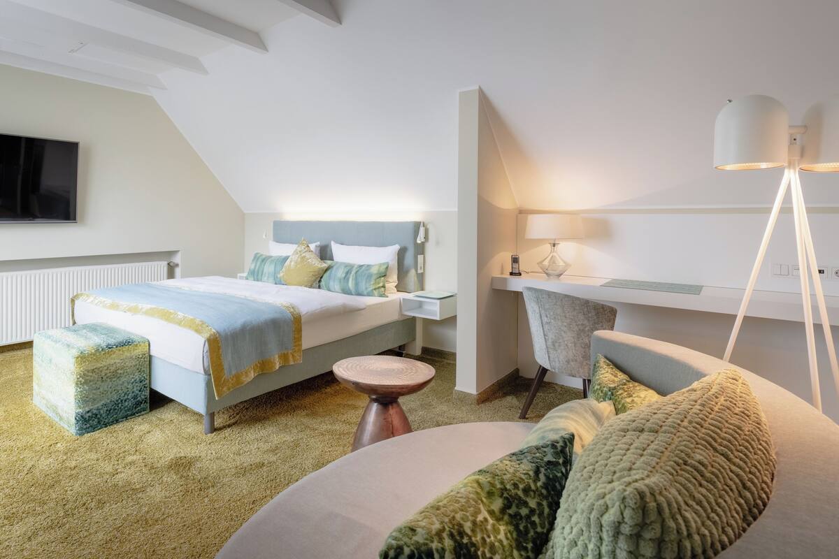 A modern bedroom with a bed, bedside table, lamp, and a view of the city.