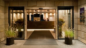 Un espace d’accueil d’hôtel au design moderne, comprenant un comptoir d’accueil, un coin salon et des plantes en pot.