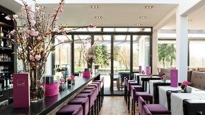 Un espace bar moderne doté d’un long comptoir, de nombreux tabourets et d’une grande fenêtre offrant une vue sur l’extérieur.