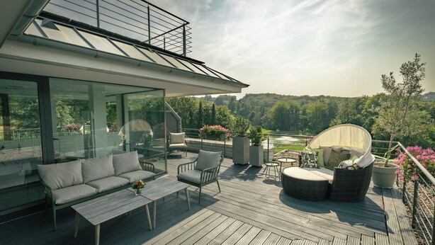 Une terrasse extérieure moderne, aménagée avec un canapé, des fauteuils et une table.