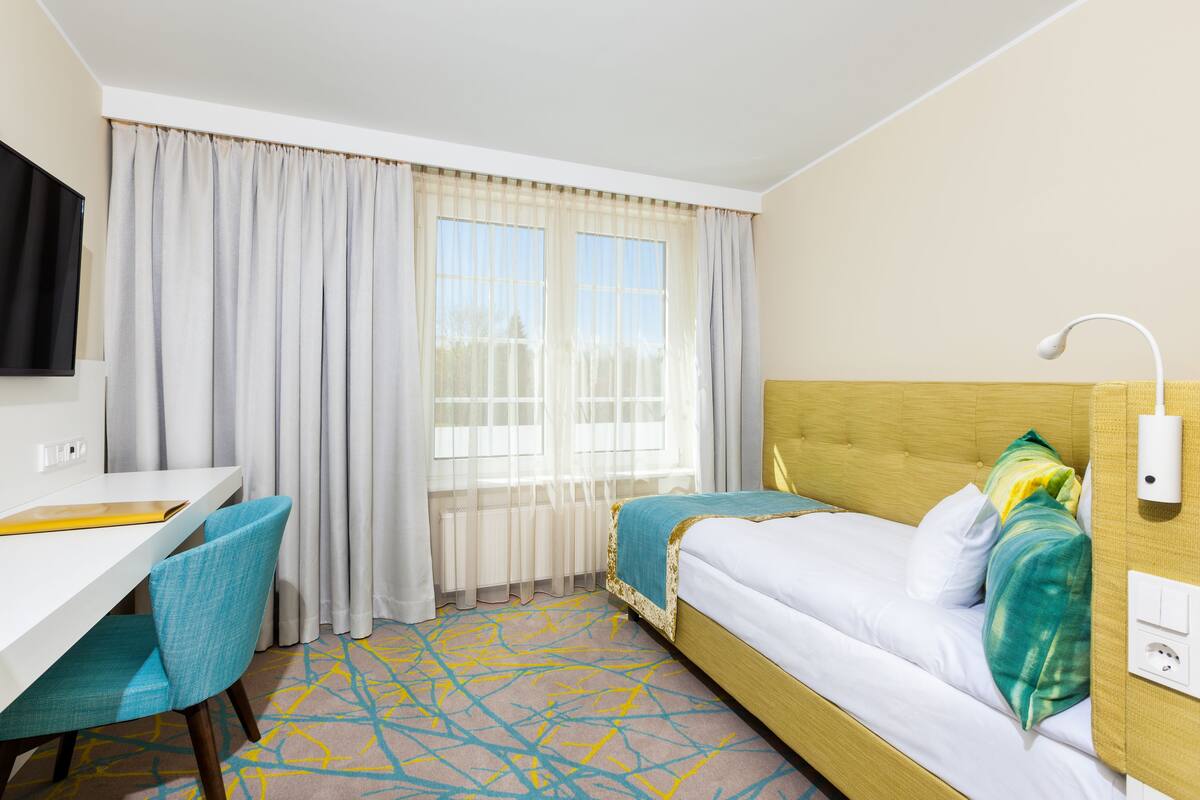 A hotel room with a bed, a desk, and a chair.