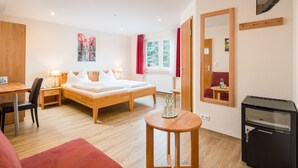 A hotel room with a bed, desk, chair, and a small table with bottles. - Garni-Hotel Bonnem-Inn (Bornheim)
