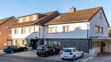 Hotel amb un disseny modern, amb façana de maó i teulat pla. Hi ha tres cotxes aparcats al davant, i l'hotel té un rètol que indica que és un hotel.
