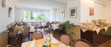 A dining area with multiple tables set for service, chairs, and a buffet counter.