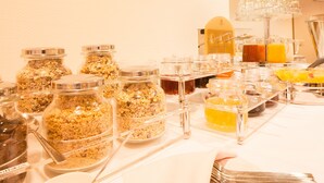 Una mesa de buffet con diversas opciones de comida y bebida, incluyendo tarros de granola y jugo.