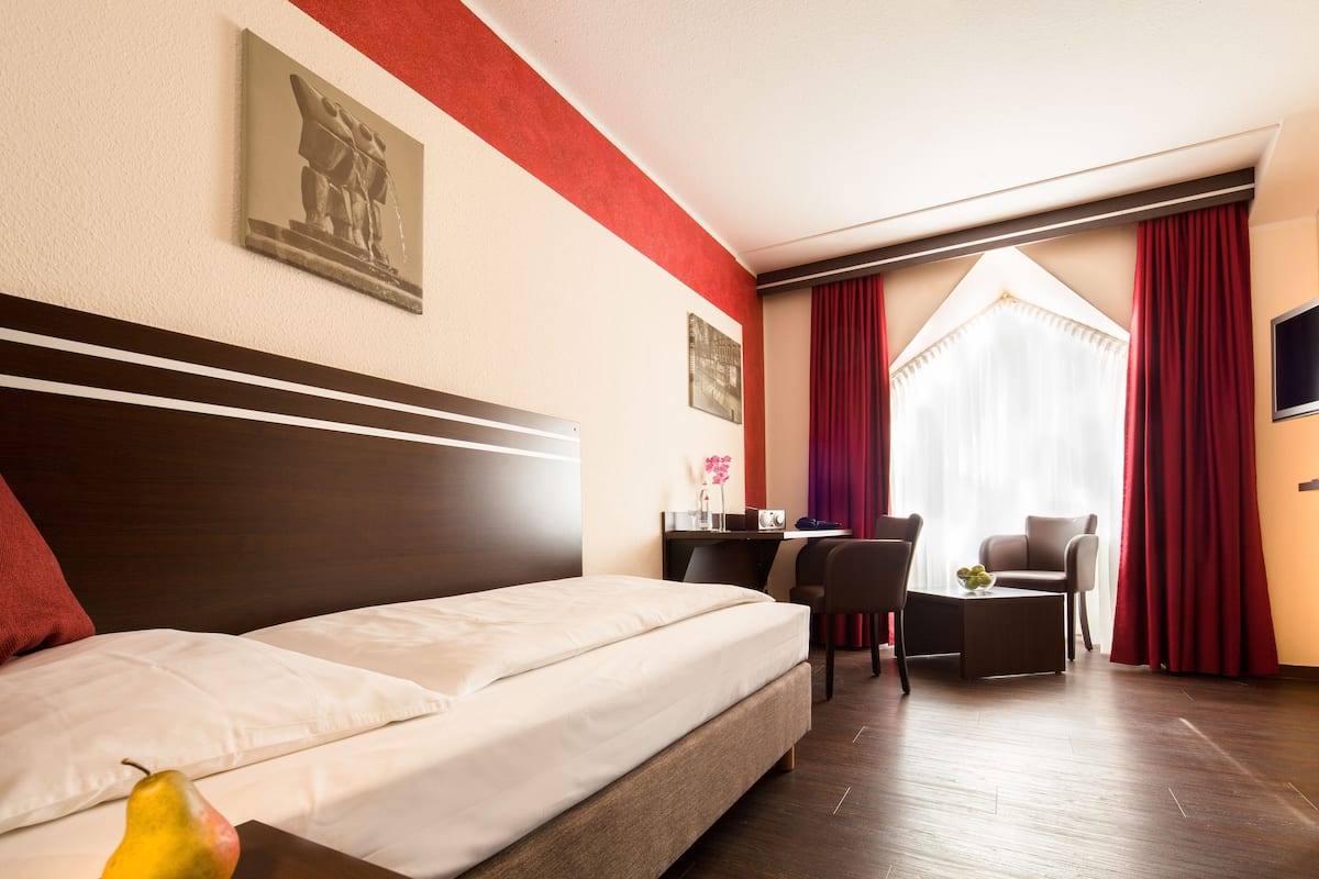 Une chambre d’hôtel avec un lit, un bureau, une chaise et un téléviseur.