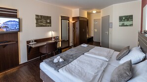 Una habitación de hotel con una cama grande, un escritorio, una silla, un televisor y un armario.