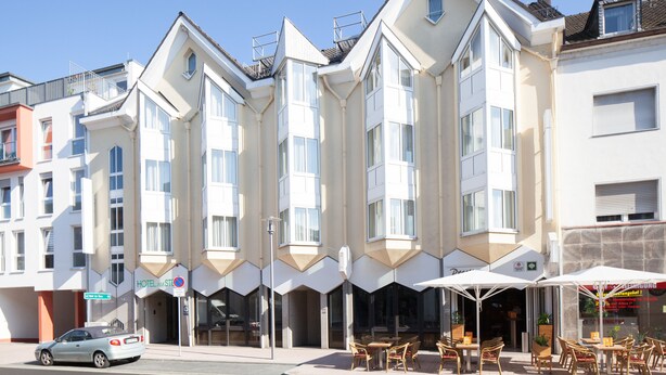 Un hotel de diseño moderno, con amplios ventanales y techo plano. Cuenta con zonas de estar al aire libre y sombrillas.