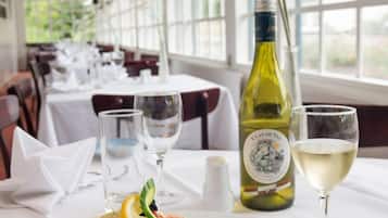Una mesa de comedor dispuesta con un plato de comida, una botella de vino y una copa de vino.