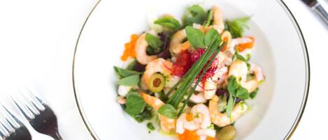 A plate of shrimp salad with greens and a garnish.