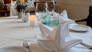 A dining table set with white tablecloths, glassware, and folded napkins. - Den Gamle Grænsekro (Christiansfeld)
