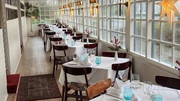 A long dining area with tables set for service, large windows, and a star decoration.
