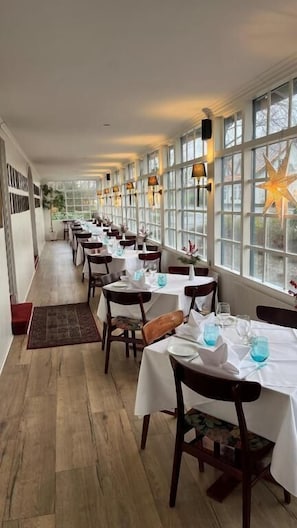 A long dining area with tables set for service, large windows, and a star decoration. - Den Gamle Grænsekro (Christiansfeld)