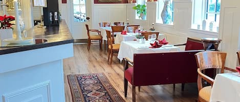 Un comedor con mesas de madera, sillas y un tapete estampado.