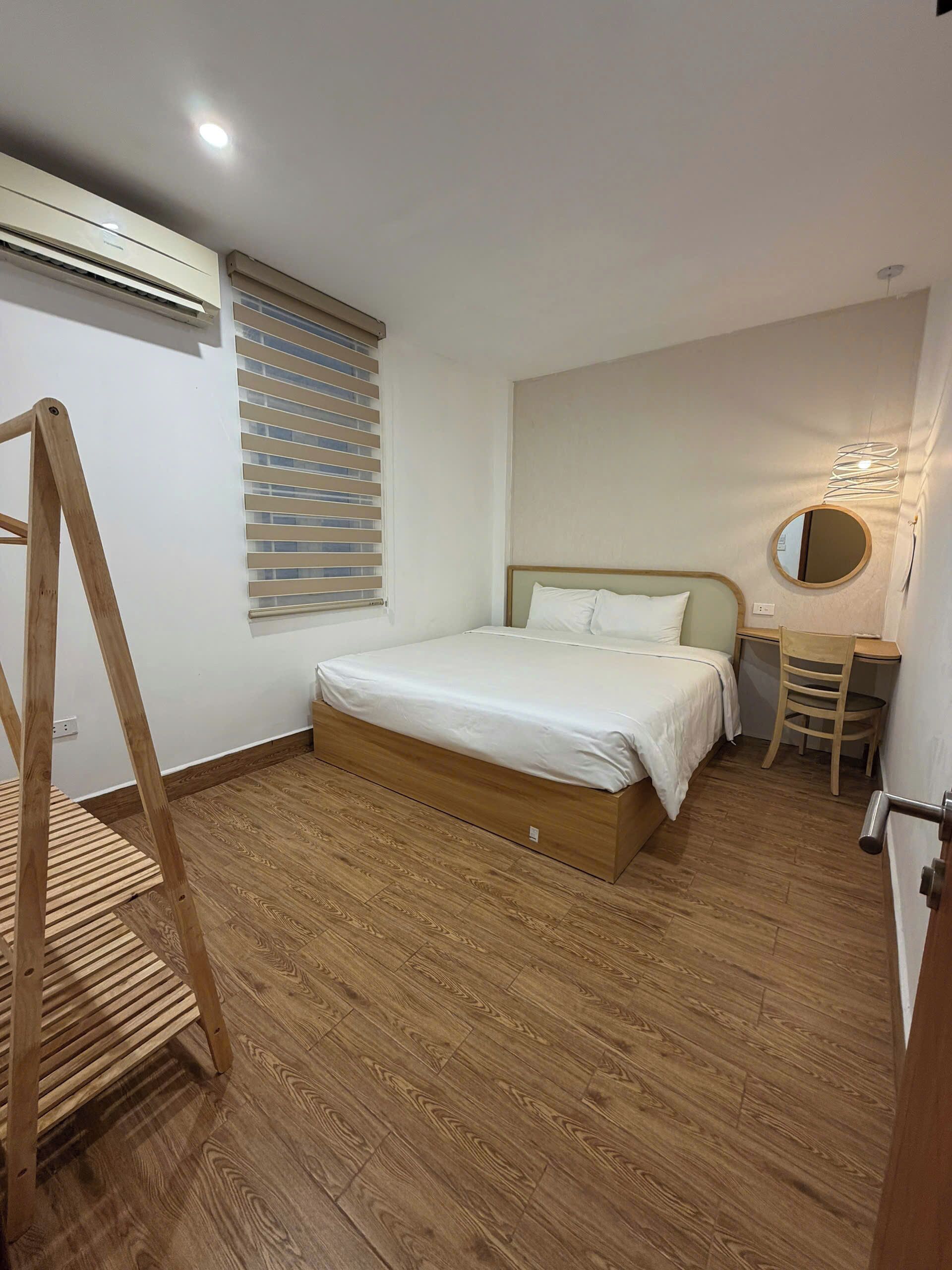 Une chambre à coucher avec un lit, un bureau, une chaise, une échelle et une fenêtre avec des stores.