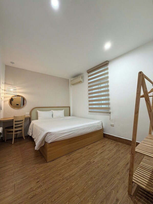 Un dormitorio con una cama de madera, un escritorio con una silla, un espejo y una ventana con persianas.