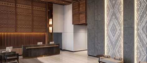 Un moderno vestíbulo de hotel con mostrador de recepción, zona de estar y paneles decorativos en la pared.