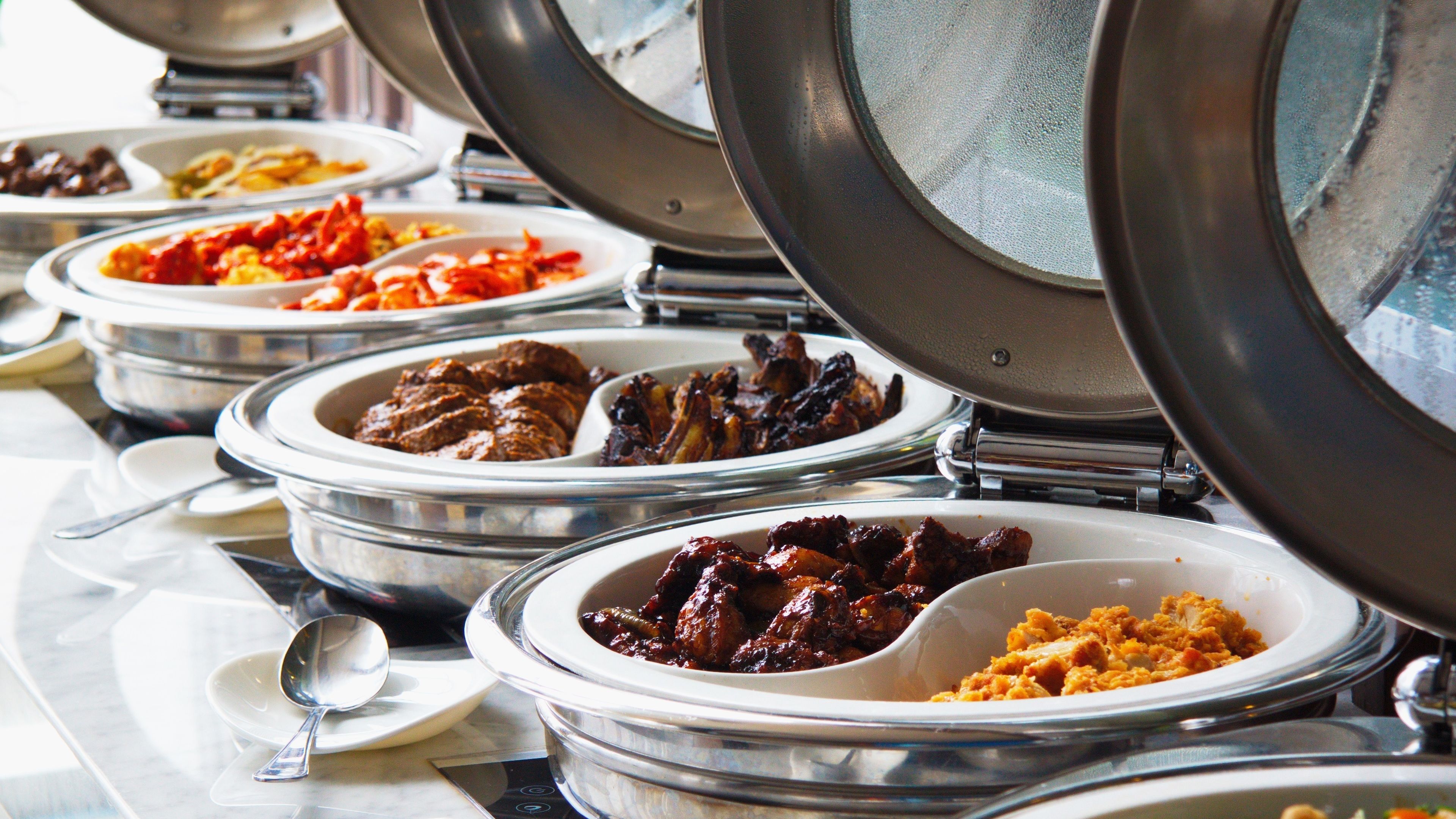 A buffet with various dishes in metal serving dishes.