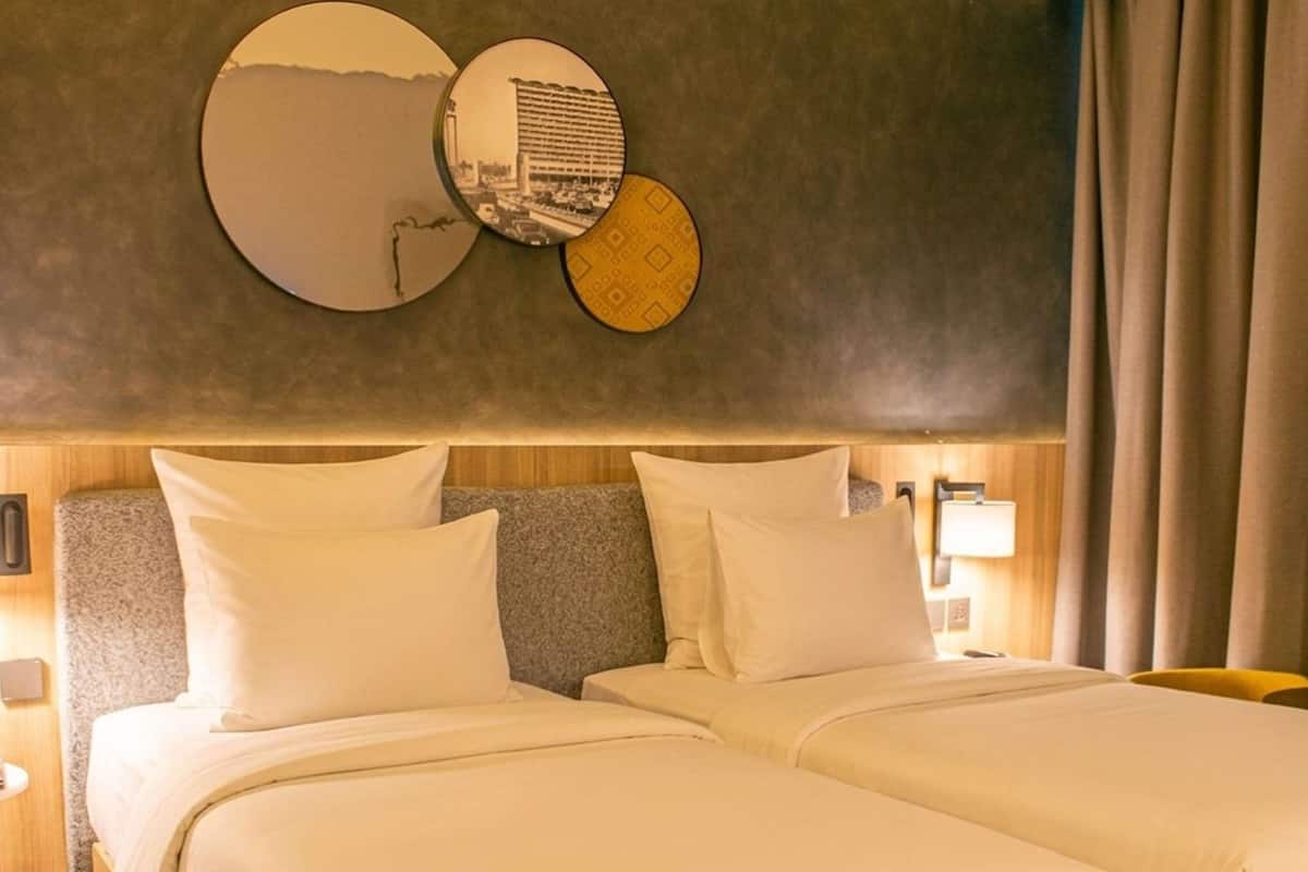 Ein Hotelzimmer mit zwei Betten, einem großen Spiegel und einer Wandlampe.