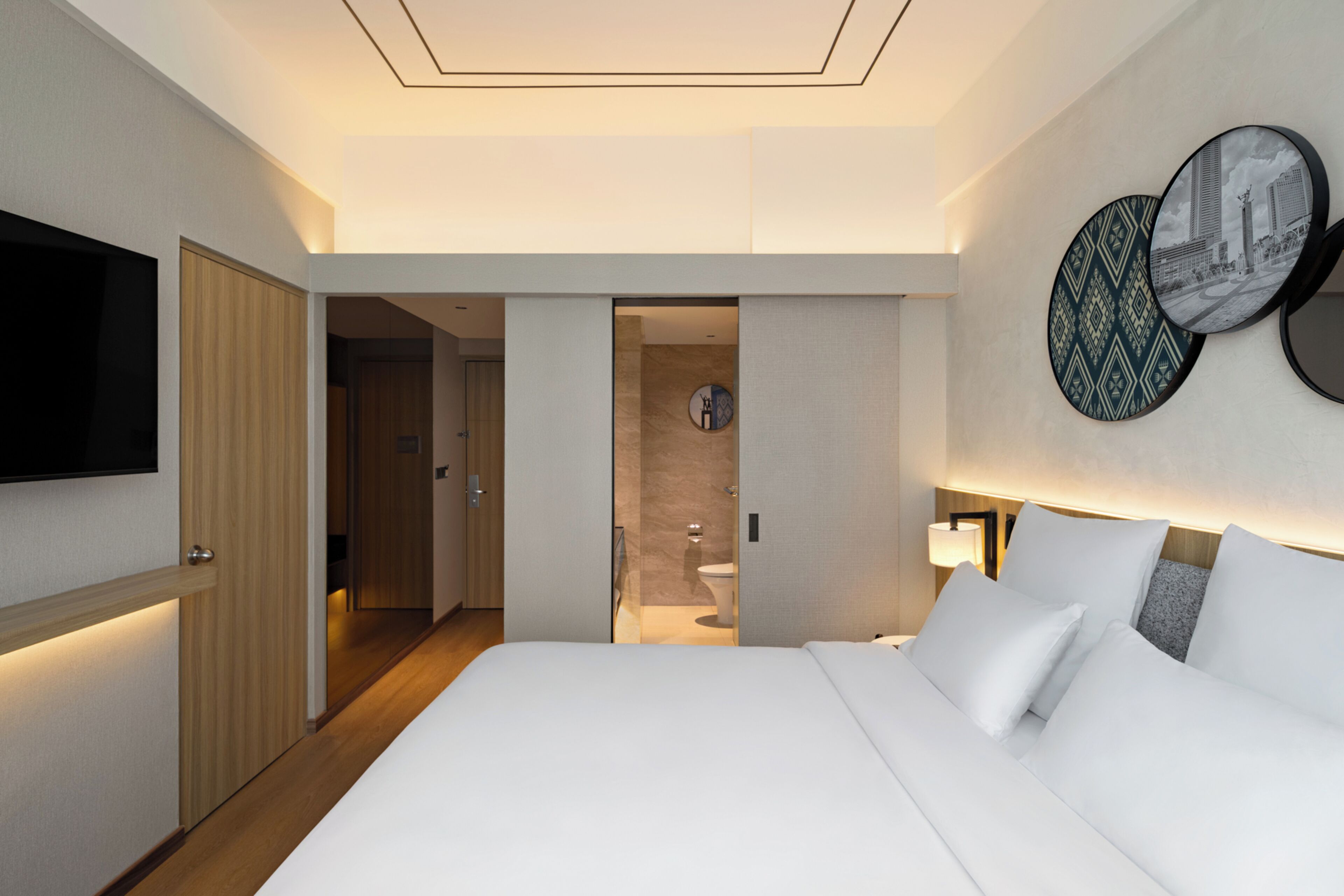Una habitación de hotel con una cama grande, un televisor en la pared y una puerta que da a un baño.