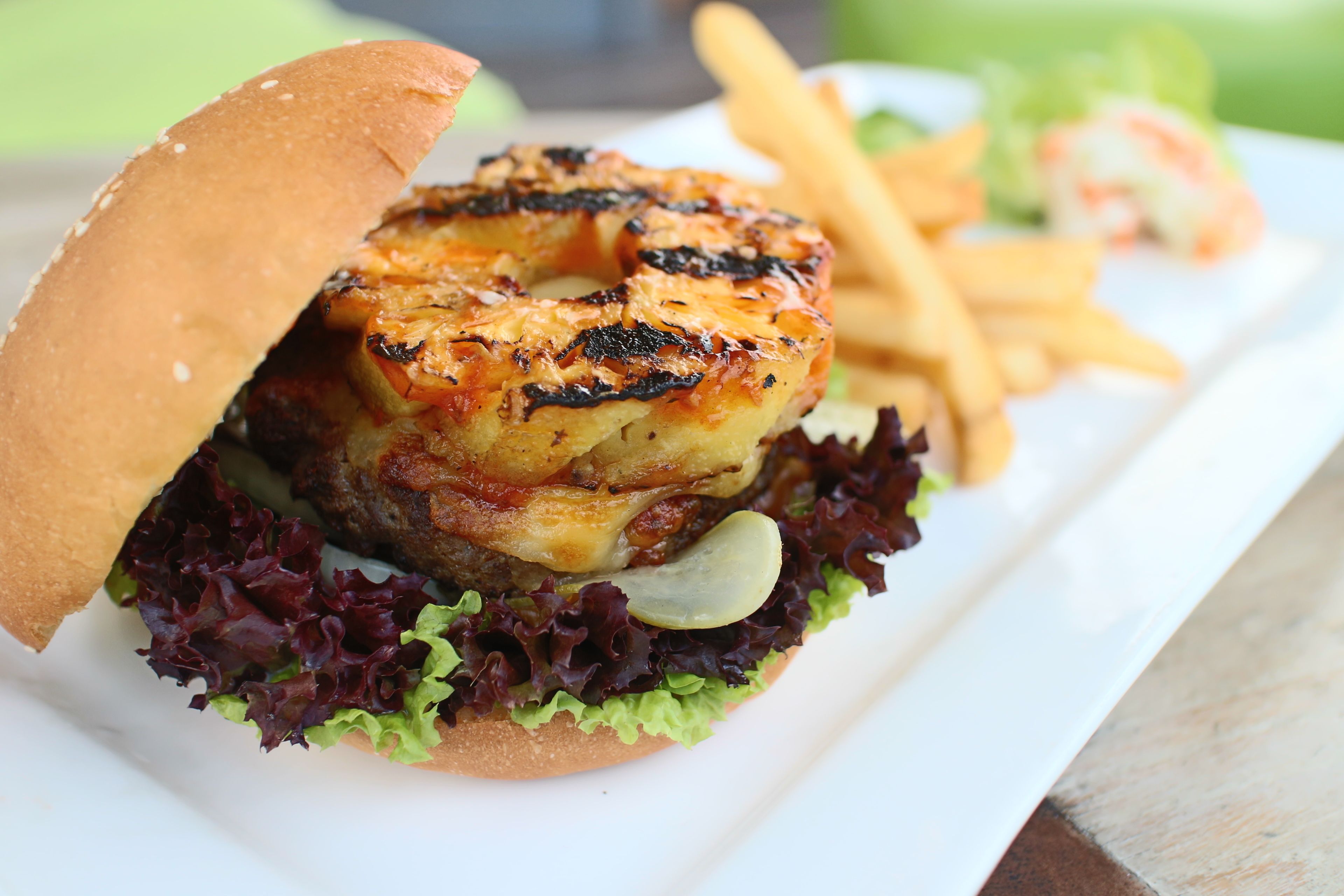 A sandwich with a grilled patty, lettuce, and a bun, accompanied by fries and a salad.