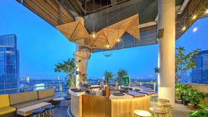Un bar situé sur le toit, avec un comptoir en bois, un espace salon et une vue sur la ville.