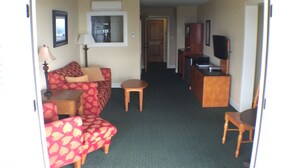A compact living area with a sofa, a small table, a television, and a kitchenette.