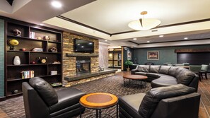 A modern living room with a fireplace, leather sofas, a flat-screen TV, and a bookshelf. - Holiday Inn Express Hotel & Suites Butte by IHG (Butte)