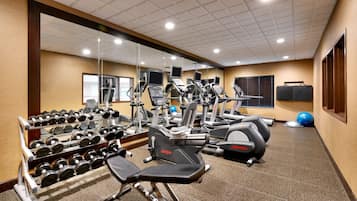 A gym with cardio machines, dumbbells, and exercise balls.